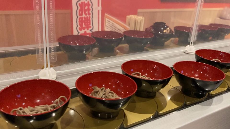 一口分ずつそばが入った漆のお椀が回転レーンに並ぶ